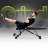 A man is performing an abdominal exercise on a black fitness bench. The word "Grind" is displayed in large, neon yellow letters in the background. Produktbild-Vorschau