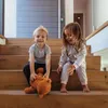 Two children sitting on wooden stairs, one holding a teddy bear. Produktbild-Vorschau