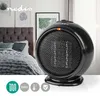 A black portable ceramic heater is displayed in a bedroom setting, with a bed and framed artwork visible in the background. Informational icons are present at the bottom of the image. Produktbild-Vorschau