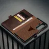A dark brown leather phone case with card slots and a honeycomb pattern with a bull logo is displayed on a textured surface. Anteprima dell’immagine prodotto