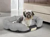 A small dog sits in a gray dog bed in a modern living room. Anteprima dell’immagine prodotto