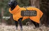 A black dog wearing an orange dog coat in an outdoor setting. Produktbild-Vorschau