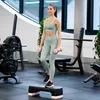 A woman is exercising with dumbbells on a step in a gym. Produktbild-Vorschau