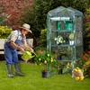 A man watering a lemon tree in a garden, with a greenhouse in the background. Produktbild-Vorschau
