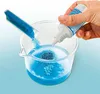 A hand is pouring blue glitter from a test tube into a beaker of blue liquid, while also squeezing a bottle of clear liquid into the beaker. Anteprima dell’immagine prodotto