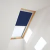 A dark blue roller blind partially covers a skylight window with a wooden frame, set against white walls. Produktbild-Vorschau