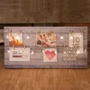 A string of fairy lights is draped across a wooden board, holding several photos and decorative cards. Produktbild-Vorschau