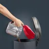 A person is emptying the dustbin of a vacuum cleaner into a trash can. Voir les images du produit