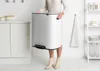 A woman is holding a large white Brabantia Bo trash can in a kitchen setting. Náhľad obrázku produktu