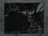 A black marble cutting board is placed on a dark textured surface. Náhľad obrázku produktu