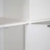A close-up view of a white shelf with a magnetic catch attached to the underside. Náhľad obrázku produktu