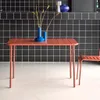 A terracotta colored outdoor table with two blue vases and dried flowers on it, set against a black tiled wall. Produktbild-Vorschau
