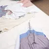 Clothes laid out on a bed or flat surface, some on hangers. Produktbild-Vorschau