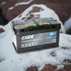 A car battery sits on a snowy, rocky surface, suggesting it is designed for cold weather conditions. Produktbild-Vorschau