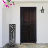 A welcome sign stands in front of a dark wooden door, with pink flowers hanging above. Produktbild-Vorschau