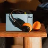 A blue portable cassette player with orange headphones rests on a wooden surface. Náhled obrázku produktu