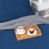 A tray with a cup of coffee and a cupcake is placed on a dark blue bed with a gray blanket. Produktbild-Vorschau