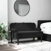 A black velvet bench with tufted detailing is placed in a bedroom setting next to a bed and a potted plant. Náhľad obrázku produktu