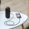 A black speaker is connected to a smartphone on a white table. Anteprima dell’immagine prodotto