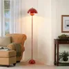 A living room scene featuring a red floor lamp, a brown armchair with an ottoman, and a side table. Anteprima dell’immagine prodotto