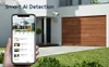 A hand holding a smartphone displaying a security camera app, with a house and garage in the background. Produktbild-Vorschau