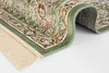A close-up view of a corner of a green rug with a floral pattern and fringe. Produktbild-Vorschau