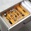 A wooden cutlery organizer filled with silverware is placed inside an open drawer. Náhľad obrázku produktu