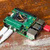 A Raspberry Pi 5 Pi M.2 HAT+ with an M.2 SSD installed, connected to cables and a USB drive, resting on a wooden surface. Anteprima dell’immagine prodotto