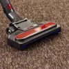A close-up shot of a vacuum cleaner head on a brown carpet. Náhled obrázku produktu