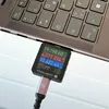 A close-up of a USB-C power meter plugged into a laptop's USB port, displaying charging information. Produktbild-Vorschau