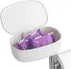 A white plastic storage box with a lid open, containing two individually wrapped sanitary pads, is shown attached to a toilet paper holder. The background is white. Náhled obrázku produktu