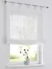 A white sheer curtain with a subtle embroidered pattern hangs over a window, with a vase of dried flowers and a small decorative object on the windowsill below. Produktbild-Vorschau