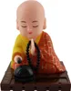 A solar-powered Wackelfigur (wobble figure) of a Buddha monk. Produktbild-Vorschau