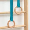 Two wooden rings with teal straps hang from a wooden wall-mounted climbing frame. Náhľad obrázku produktu