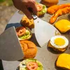 A person is using spatulas to assemble burgers on a grill. Podgląd zdjęcia produktu
