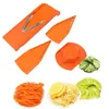A collection of orange plastic mandolin slicer attachments and various sliced vegetables, including carrots, potatoes, and cucumber, arranged on a white background. Anteprima dell’immagine prodotto