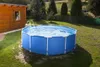 An above-ground swimming pool is set up in a grassy backyard next to a wooden shed. Náhled obrázku produktu