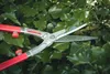A close-up of hedge shears cutting through green ivy leaves. Voir les images du produit