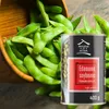 A can of edamame soybeans is placed next to a wooden bowl filled with fresh edamame pods. Produktbild-Vorschau
