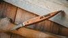 A carving knife with a wooden handle rests on a wooden surface. Anteprima dell’immagine prodotto