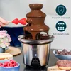 A chocolate fountain is shown with strawberries being dipped into it, surrounded by other dessert items like marshmallows, ladyfingers, raspberries, and a donut. There are also informational icons and text on the right side. Podgląd zdjęcia produktu