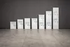 A row of white washbasins of varying sizes lined up against a dark gray wall. Anteprima dell’immagine prodotto