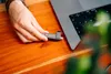 A hand is inserting a USB drive into a laptop. Náhľad obrázku produktu