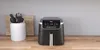 An air fryer is placed on a wooden countertop next to a white utensil holder filled with kitchen tools. Náhled obrázku produktu