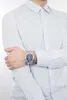 A man wearing a light blue dress shirt and a silver and blue watch. Produktbild-Vorschau