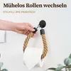 A hand is shown holding a toilet paper holder made of rope, which has a roll of toilet paper on it. The holder is attached to a wall. Anteprima dell’immagine prodotto