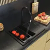 A modern kitchen sink with tomatoes being washed under a black faucet. Produktbild-Vorschau