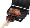 A hand is shown pulling out the drip tray of a black electric grill with a steak cooking on it. Produktbild-Vorschau
