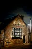 A stone building with the name 'Glen Garioch Distillery' above a large window, at night. Produktbild-Vorschau
