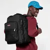 A young man wearing a blue cap and a maroon sweatshirt is carrying a black Eastpak rucksack. Produktbild-Vorschau